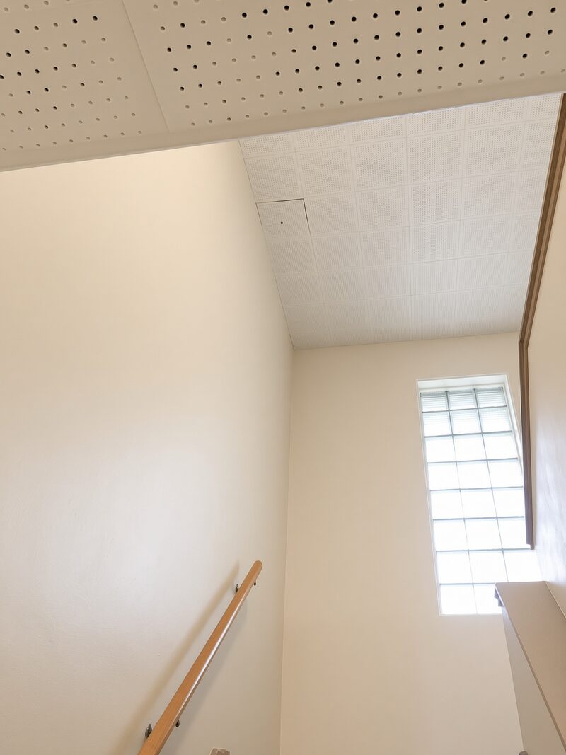 Stair landing with a tall window, walls carried up to the sloped ceiling line.