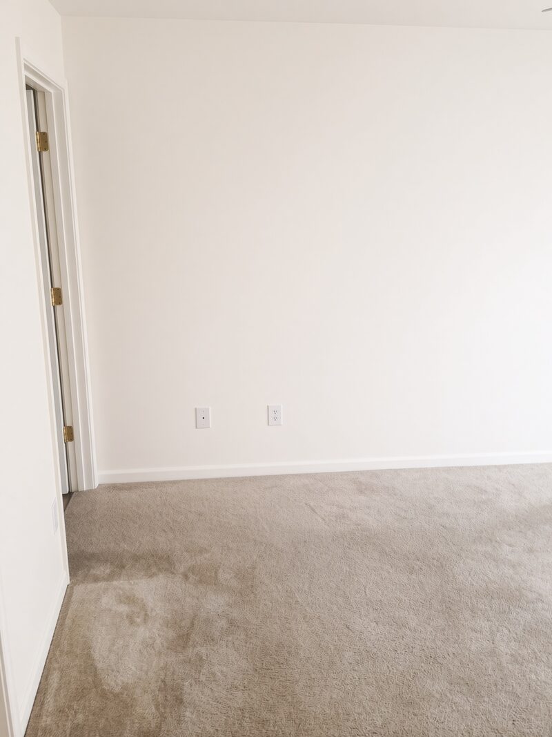 Empty bedroom wall rolled flat, outlets and door edge cut in clean.
