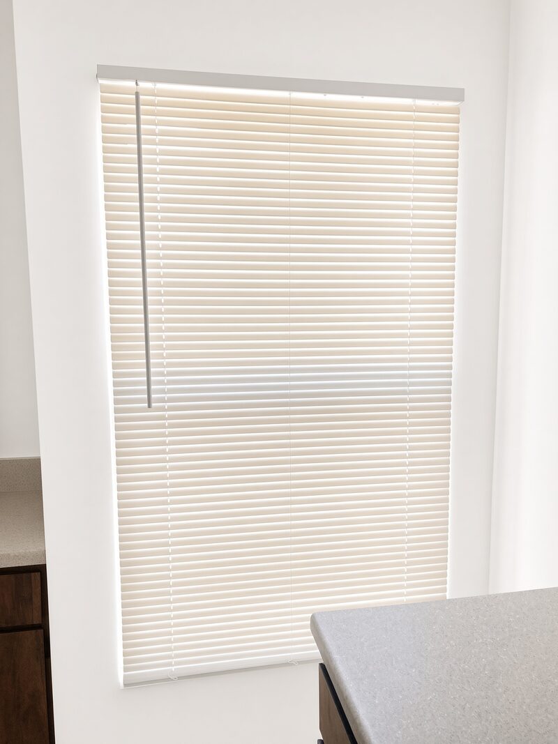 White blinds at a window with the wall and sill finished.