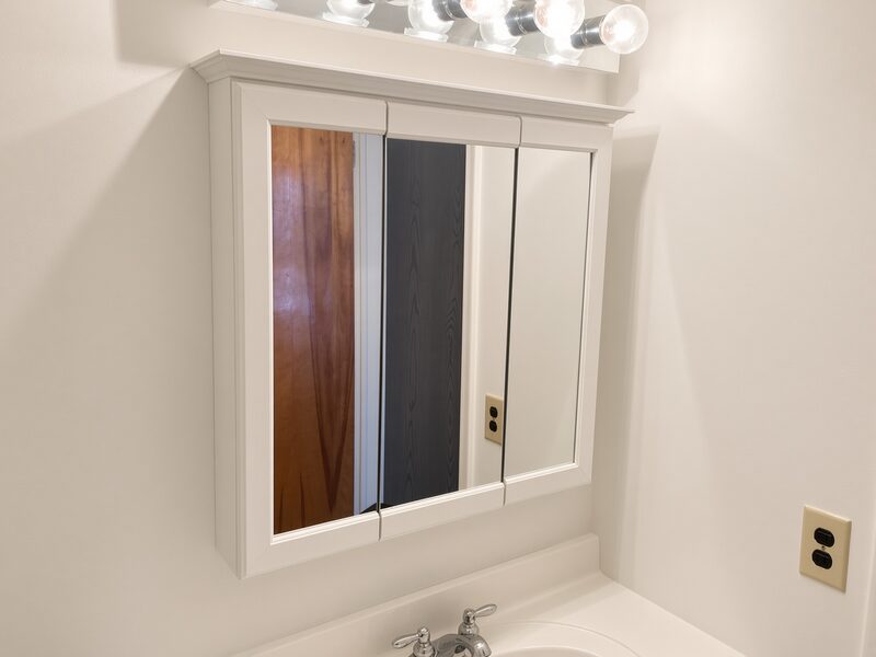 Bathroom mirrored cabinet and light bar with the wall painted around them.