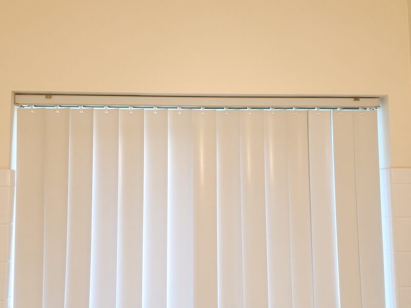 Vertical blinds below a cream wall carried up to the ceiling line.