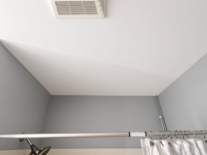 Grey bathroom walls meeting a white ceiling, curtain rod back up.