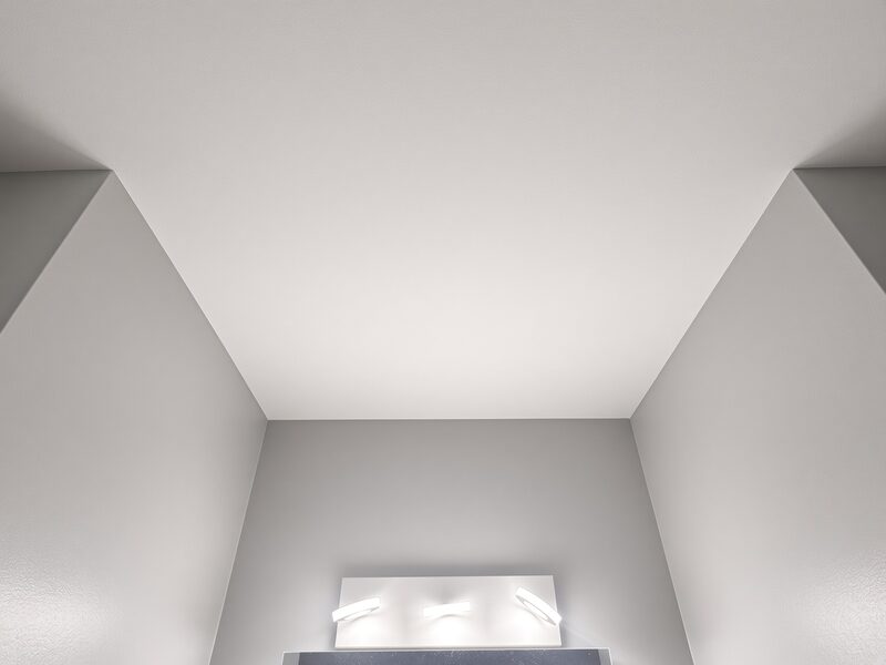 Grey walls carried into the corner under a white ceiling above the vanity.